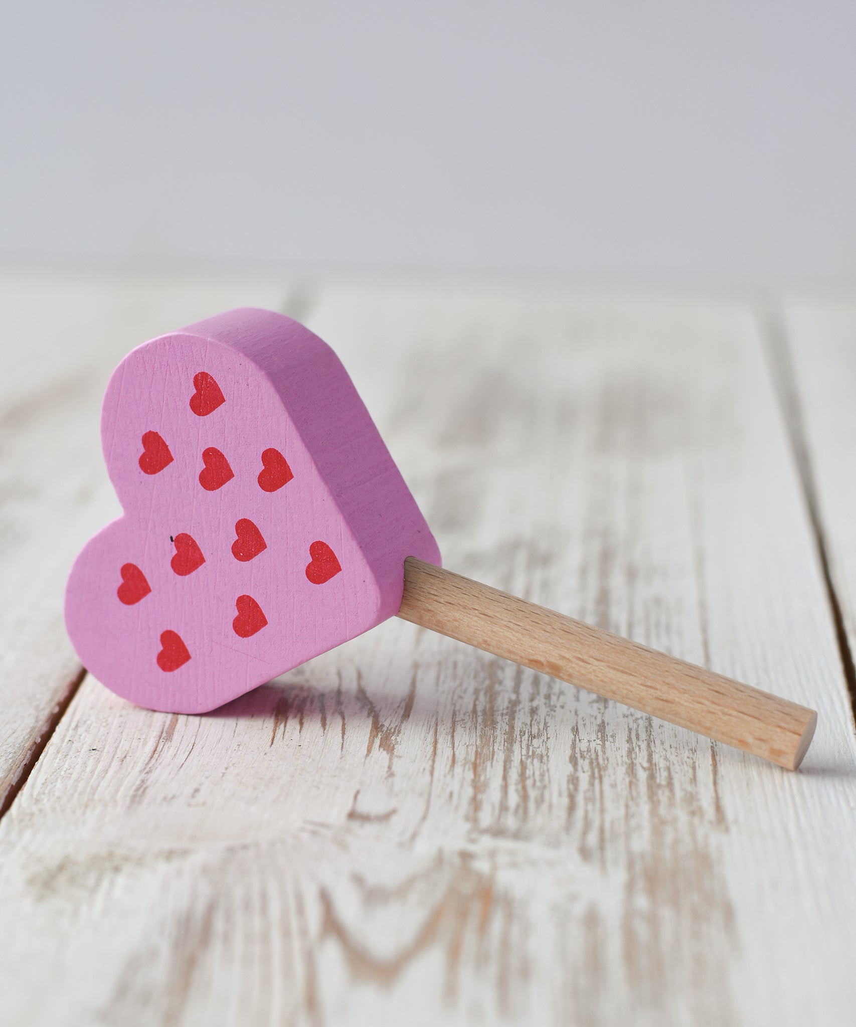Erzi pink raspberry heart shaped ice lolly wooden play food placed on a wooden surface.
