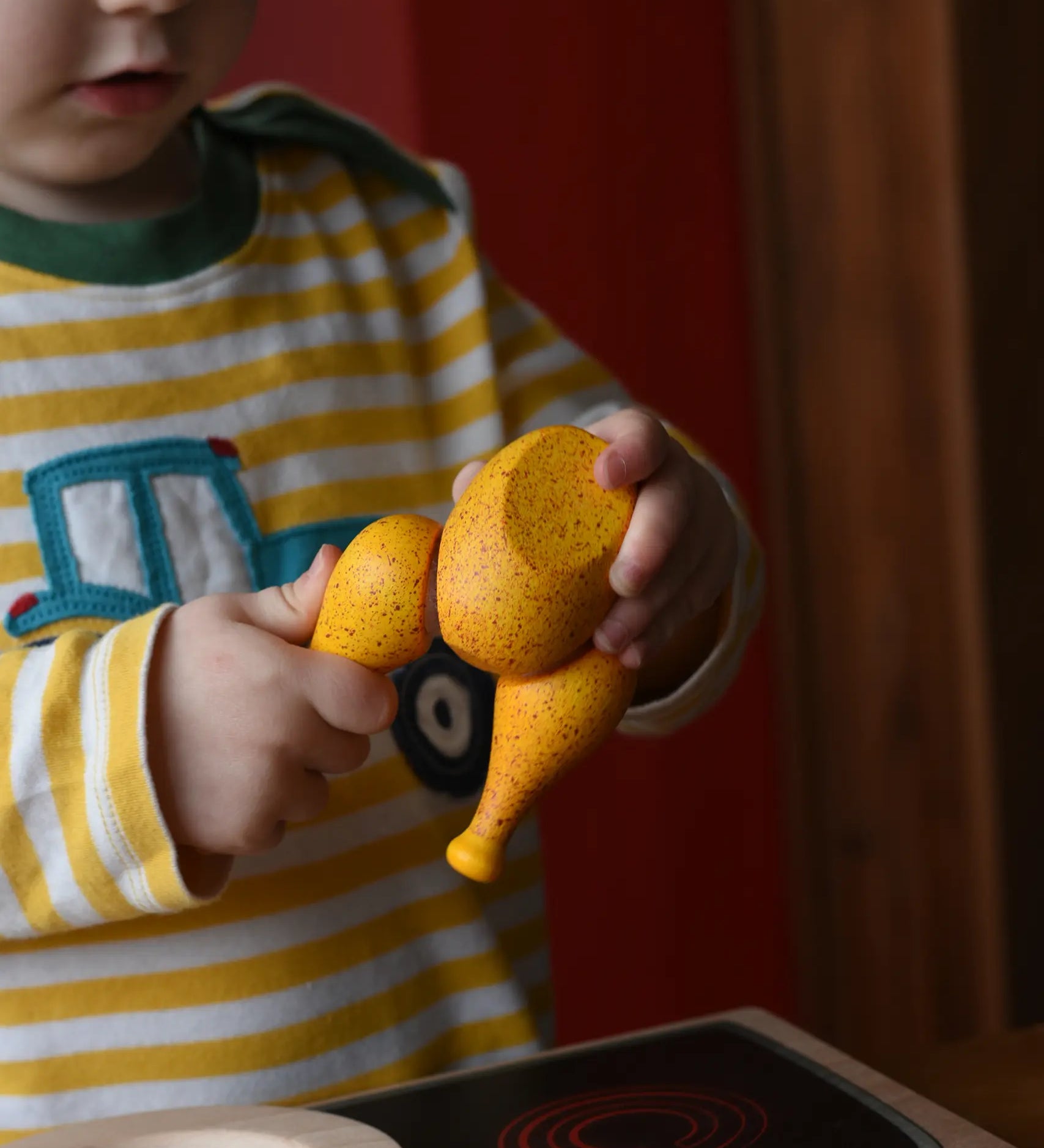 Child with the Erzi roast chicken wooden play food in their hand.