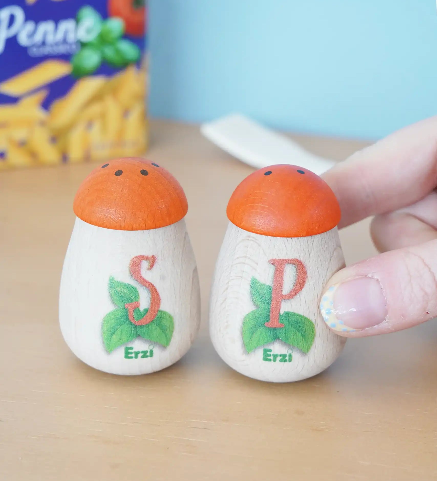 Erzi wooden play food salt and pepper shakers in the Babipur playroom. An adult's hand can be seen holding the pepper pot. 