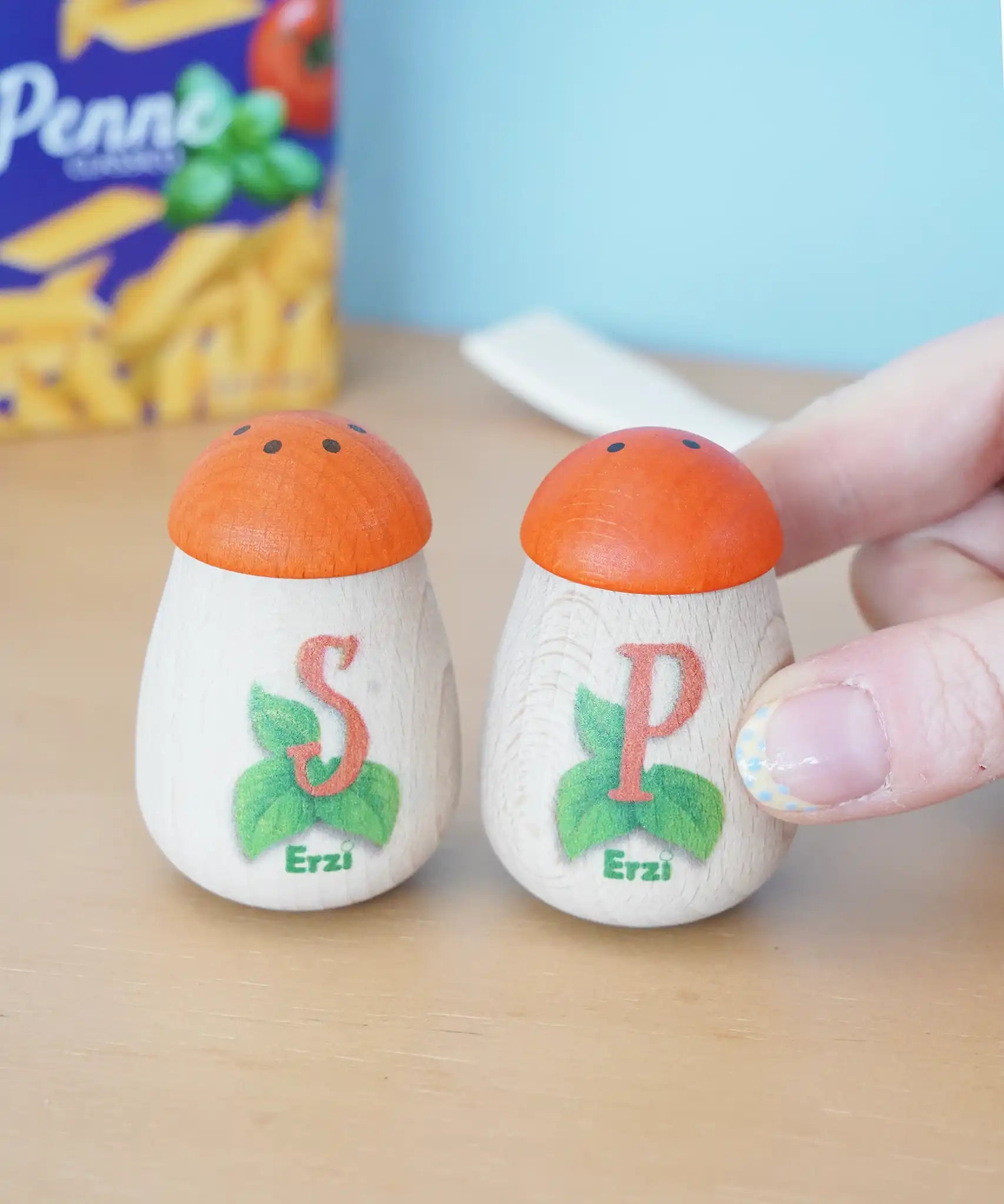 Erzi wooden play food salt and pepper shakers in the Babipur playroom. An adult's hand can be seen holding the pepper pot. 