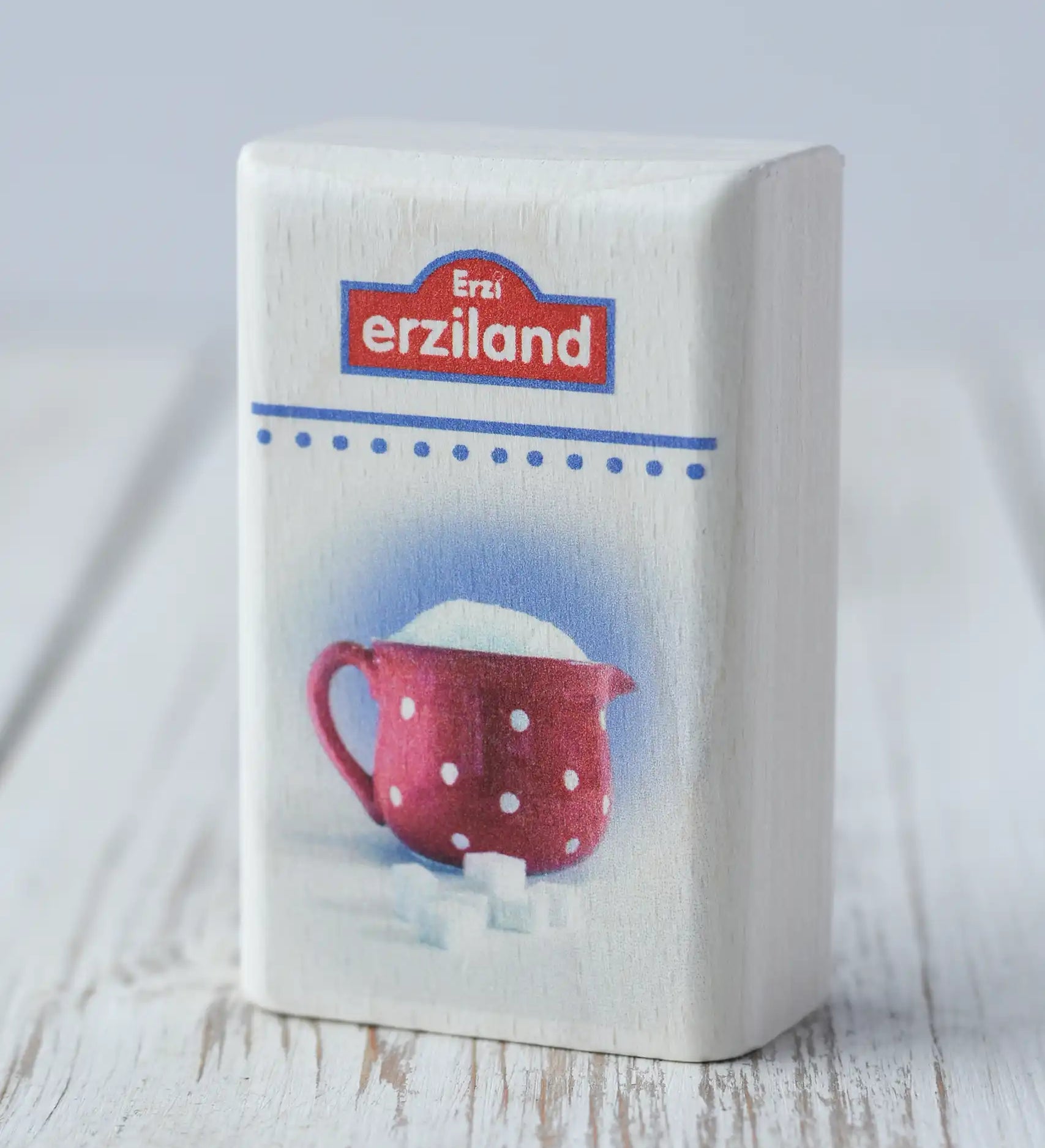 Erzi Sugar Wooden Play Food toy. White rectangular shaped wooden packed with Erzi branding and photo of sugar in a red spotted jug on the front.