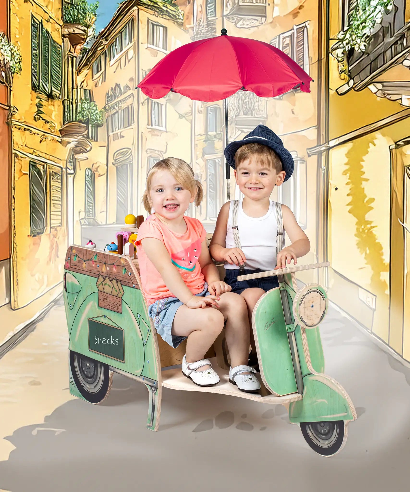 Two children sitting on the Erzi toys green wooden streetfood roller tuk tuk style food vendor vehicle against a cartoon backdrop.