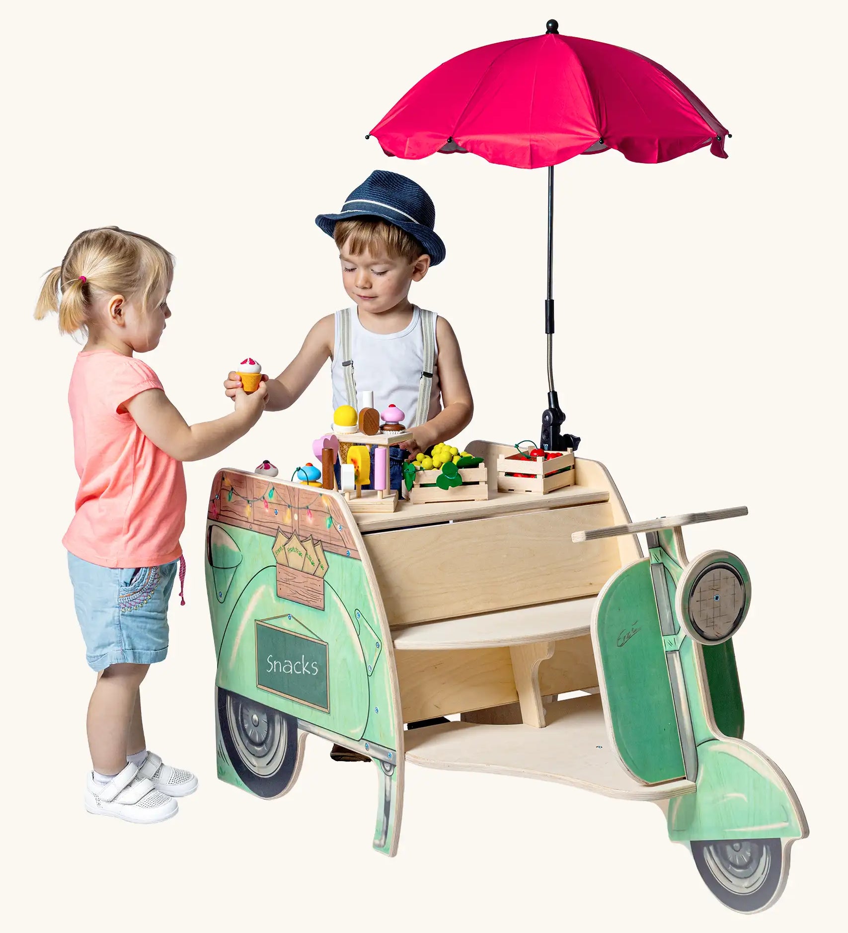 Children playing with the Erzi toys green wooden streetfood roller tuk tuk style food vendor vehicle. One child is serving ice cream from the back counter, covered in wooden play food. 
