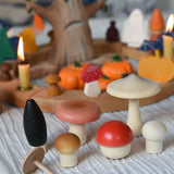 A selection of the wooden mushrooms from the Erzi Forest mushrooms in a box set placed on a striped tablecloth in front of an Autumnal themed Grimm's celebration ring set up. 