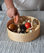 A child picking up a pink coloured mushroom from the Erzi Forest mushrooms in a box set out of the box. 