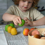 A child sitting at a table playing with Erzi wooden apples. 
