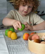 A child sitting at a table playing with Erzi wooden apples. 
