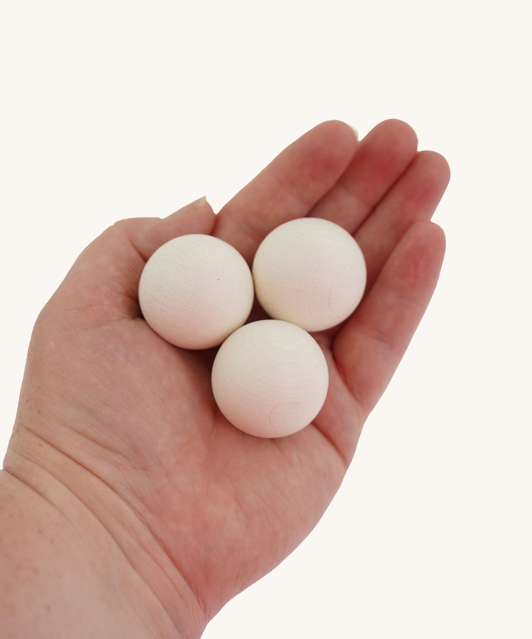 Erzi White Wooden Marbles 30mm Beech Set for Trackboards and Open-Ended Play. The three white marble are shown in an adult's hand for scale. 