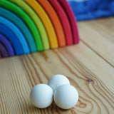 The set of three Erzi 30mm marbles placed on a wooden surface with a Grimm's rainbow in the background. 