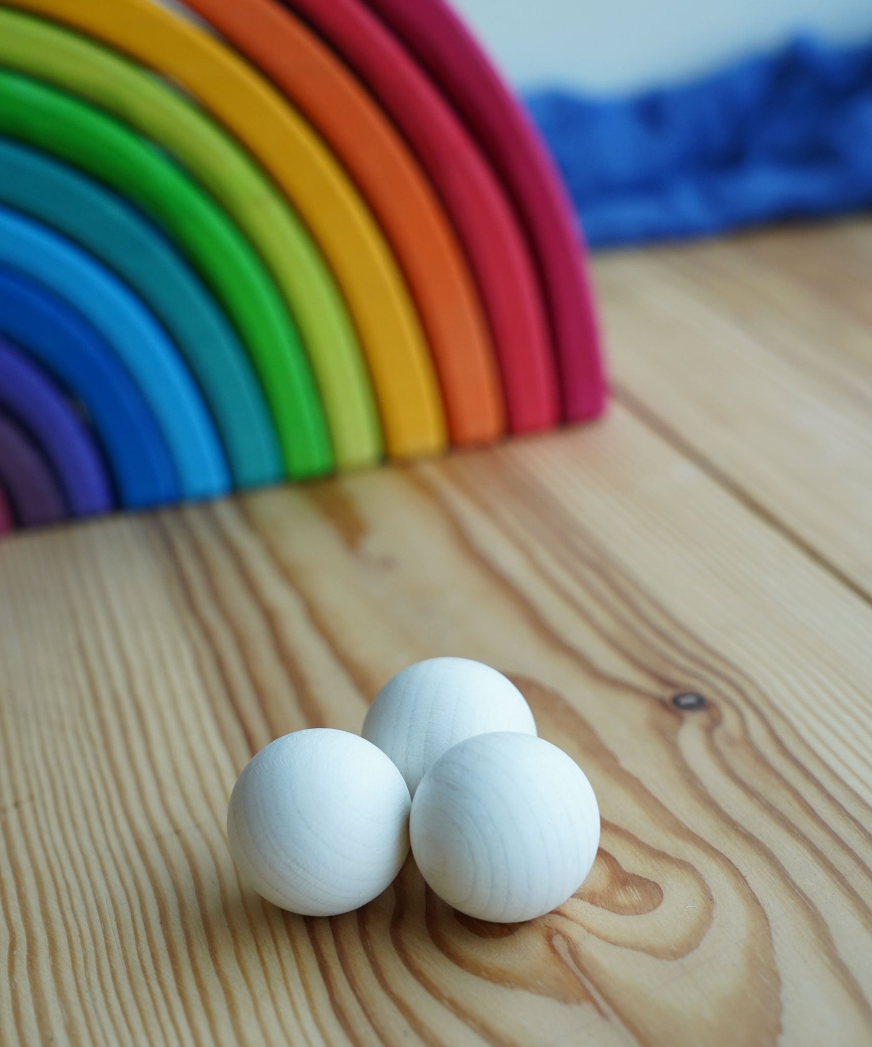 The set of three Erzi 30mm marbles placed on a wooden surface with a Grimm's rainbow in the background. 