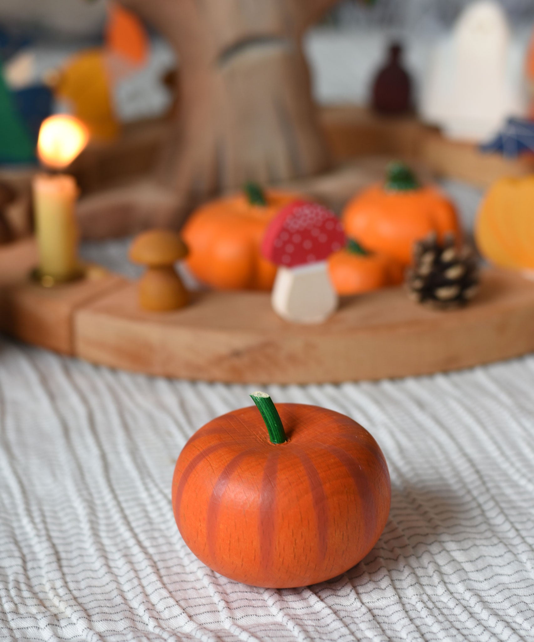An Erzi pumkin placed on a tablecloth in front of an Autumnal themed celebration ring set up. 