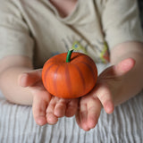 An Erzi wooden toy pumpkin in a child's hand.