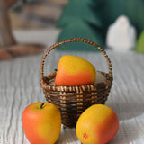 An Erzi red apple toy placed in a Kraul basket with two apples placed besides it. 