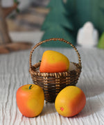 An Erzi red apple toy placed in a Kraul basket with two apples placed besides it. 