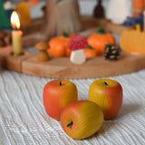Three red Erzi wooden toy apples placed in front of an Autumnal themed celebration ring.