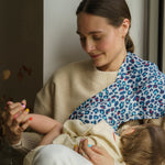 A mother holding a baby with the Etta Loves Extra Large Organic Cotton Baby Muslin Square - Blue Leopard on the shoulder