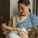 A mother holding a baby with the Etta Loves Extra Large Organic Cotton Baby Muslin Square - Blue Leopard on the shoulder