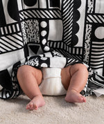 A Etta Loves x Camille Walala XL Muslin Square - Mono hung up, a baby's legs and feet can be seen popping out from underneath.