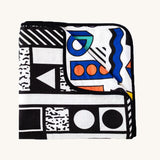 Etta Loves x Camille Walala Muslin Blanket folded into a square with one corner folded down showing the coloured side. 