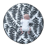 A toddler lying down on colourful Sycamore seed print on the Etta Loves Reversible Organic Cotton Baby Play Mat - Plant Print 