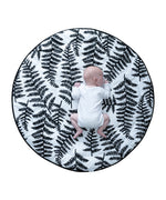 A toddler lying down on colourful Sycamore seed print on the Etta Loves Reversible Organic Cotton Baby Play Mat - Plant Print 