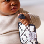 A baby holding a Etta Loves sensory hanging square on mono design to give an idea on size