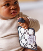 A baby holding a Etta Loves sensory hanging square on mono design to give an idea on size