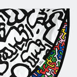 A baby lying down the the 'Brazil' side of the Etta Loves X Keith Haring Reversible Organic Cotton Baby Play Mat
