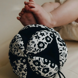 Etta Loves x Liberty organic cotton sensory grasping ball near baby feet showing scale and the Liberty pattern