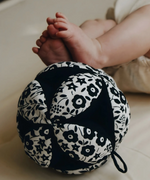 Etta Loves x Liberty organic cotton sensory grasping ball near baby feet showing scale and the Liberty pattern