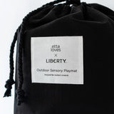 Black cotton bag with a brand patch and drawstring to hold the Etta Loves x Liberty organic cotton playmat 