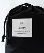 Black cotton bag with a brand patch and drawstring to hold the Etta Loves x Liberty organic cotton playmat 