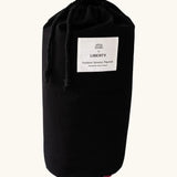 Black cotton bag with a brand patch holding the Etta Loves x Liberty organic cotton sensory colourful outdoor playmat 