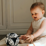 Etta Loves x Liberty organic cotton sensory grasping ball with a black inner, being played with by a child