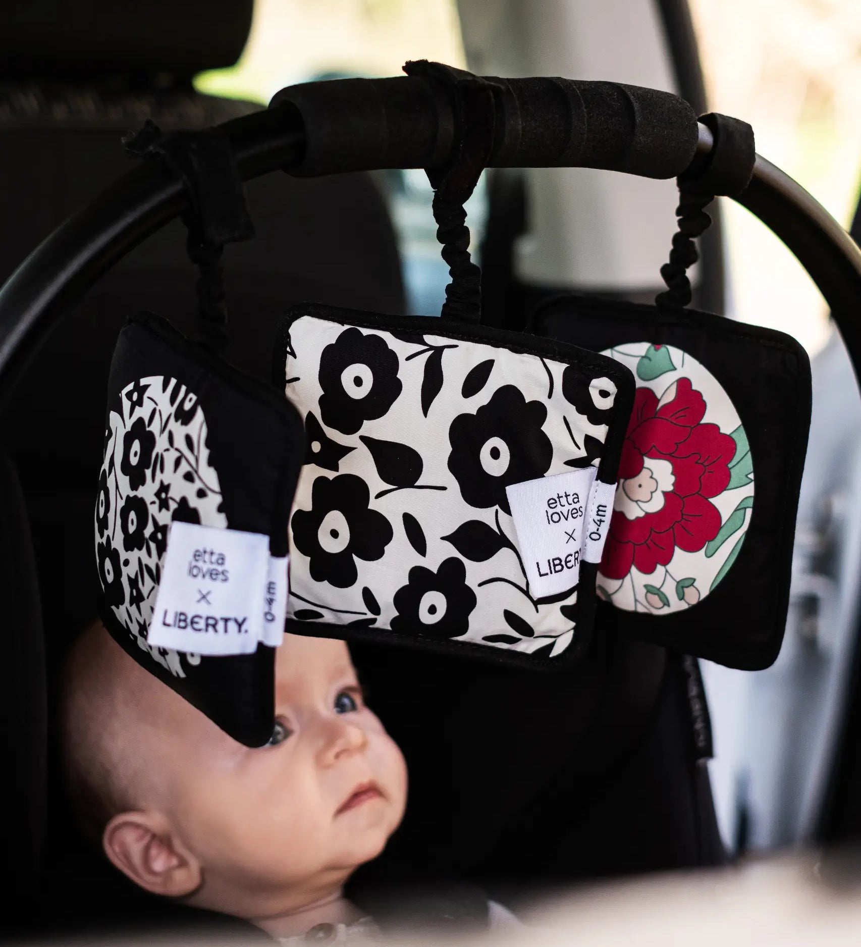 Set of 3 Etta Loves x Liberty sensory hanging squares hanging on a buggy with a baby inside