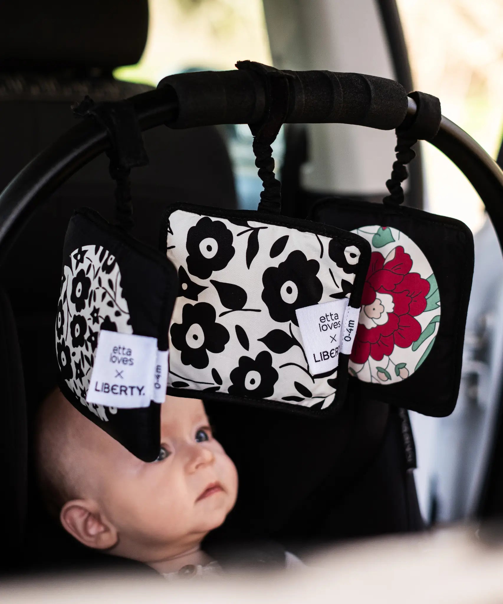 Set of 3 Etta Loves x Liberty sensory hanging squares hanging on a buggy with a baby inside