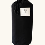 Black cotton bag with a brand patch holding the Etta Loves x Liberty organic cotton sensory monochrome outdoor playmat 