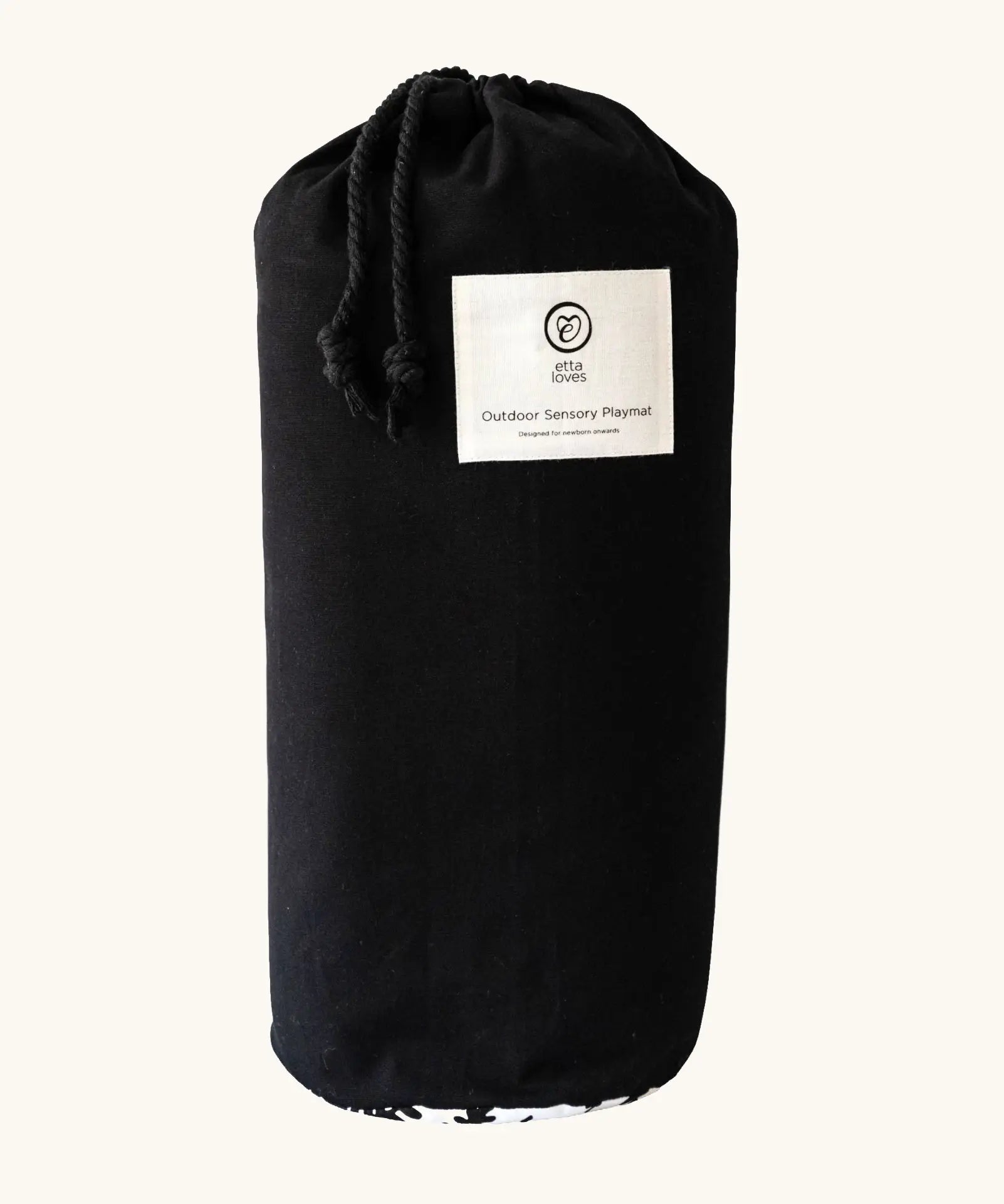 Black cotton bag with a brand patch holding the Etta Loves x Liberty organic cotton sensory monochrome outdoor playmat 