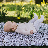 Baby lying on its back on the Etta Loves x Liberty organic cotton monochrome sensory playmat 