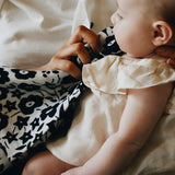 Mother holding the monochrome floral Etta Loves x Liberty muslin square cloth while feeding a baby