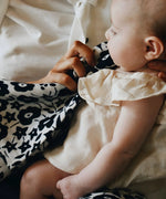 Mother holding the monochrome floral Etta Loves x Liberty muslin square cloth while feeding a baby