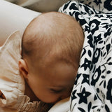 Mother feeding a baby with a Etta Loves x Liberty organic cotton muslin cloth over the head