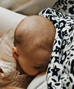 Mother feeding a baby with a Etta Loves x Liberty organic cotton muslin cloth over the head