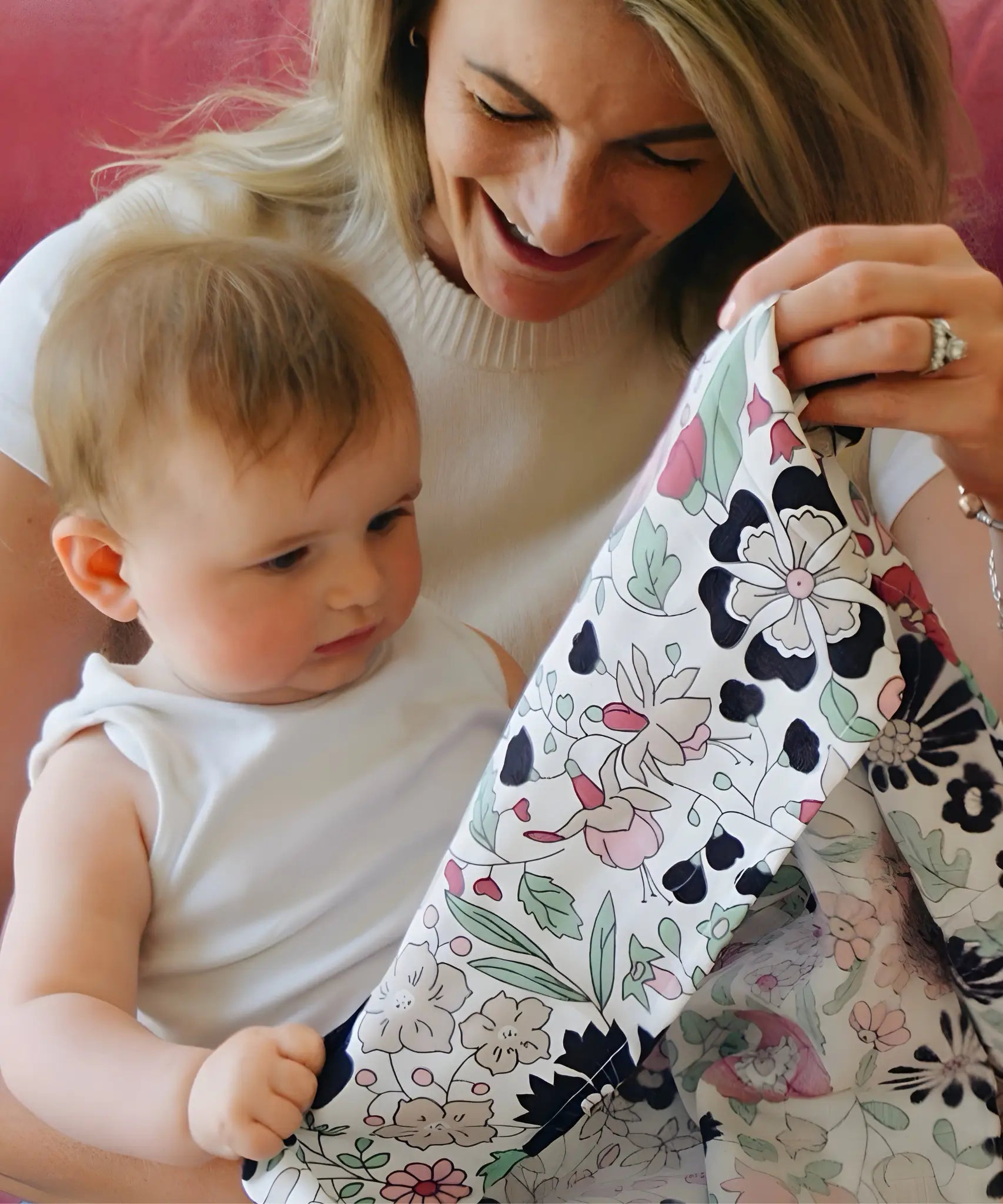 Mother holding a Etta Love x Liberty pastel floral design organic cotton muslin cloth in front of a baby. 