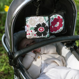 2 Etta Loves x Liberty sensory hanging squares showing the floral pastel design hanging on a buggy with a baby inside 