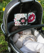 2 Etta Loves x Liberty sensory hanging squares showing the floral pastel design hanging on a buggy with a baby inside 