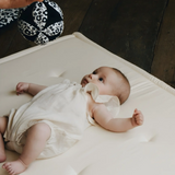 Adult holding a Etta Loves x Liberty organic cotton sensory grasping ball above a baby 