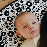 Baby lying on its back on the GOTS organic cotton Etta Loves x Liberty sensory reversible playmat showing the Fairford shadow design