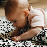 Baby having tummy time on the Etta Loves reversible sensory playmat in collaboration with showing the Fairford shadow design