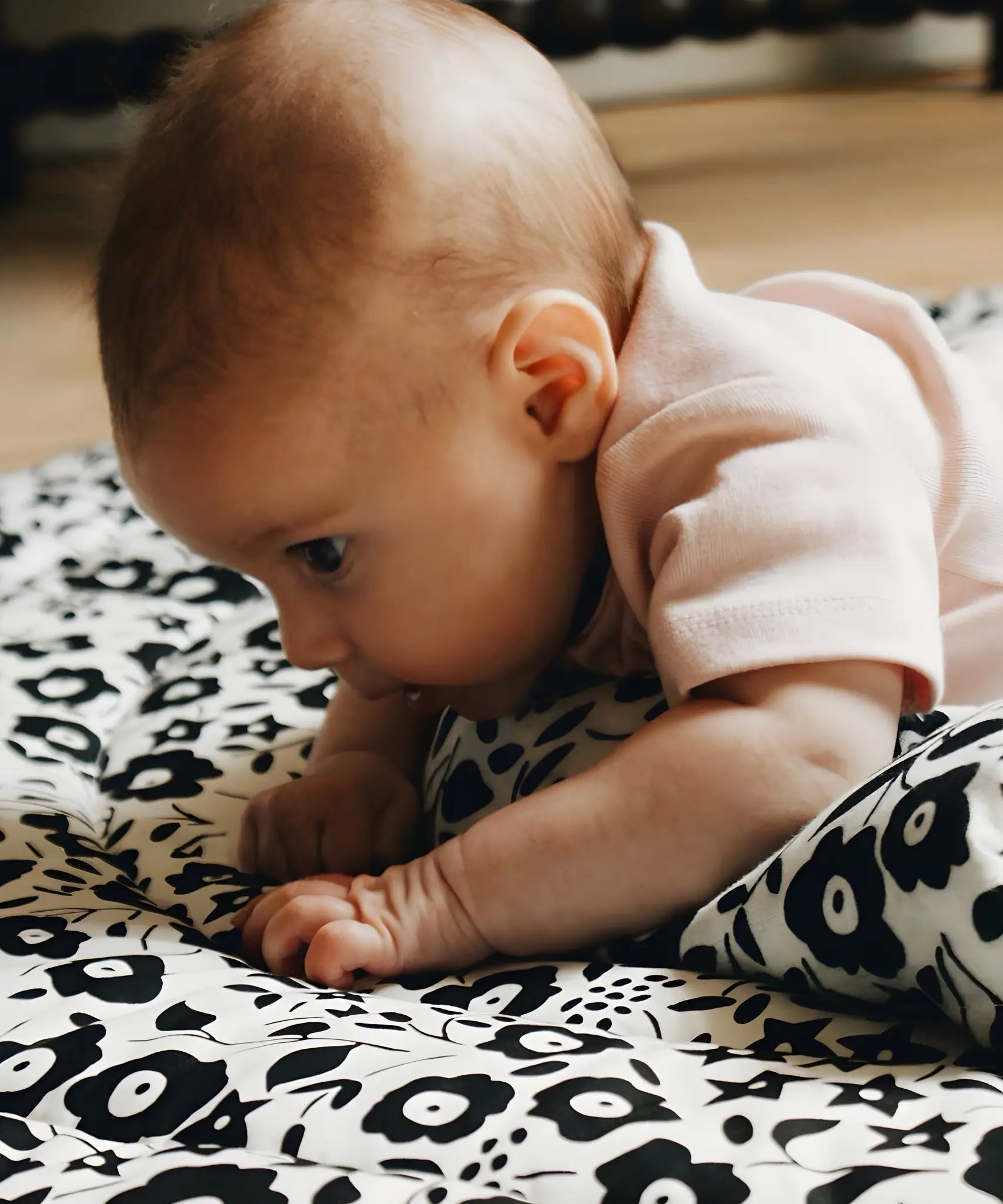 Baby having tummy time on the Etta Loves reversible sensory playmat in collaboration with showing the Fairford shadow design